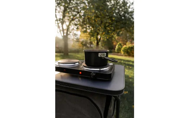 Mestic MKT-120 electric cooker on a camping table at sunset with a pot heating on top
