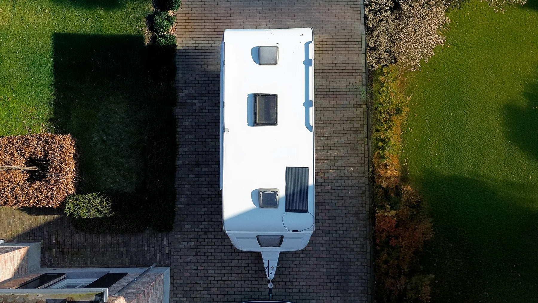 Caravan with a Mestic roof-mounted solar panel viewed from above on a residential driveway