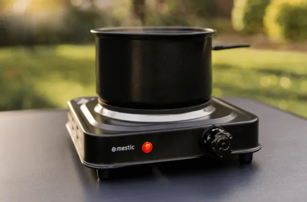 Single-burner Mestic cooker in use on a camping table — quick meals on the road