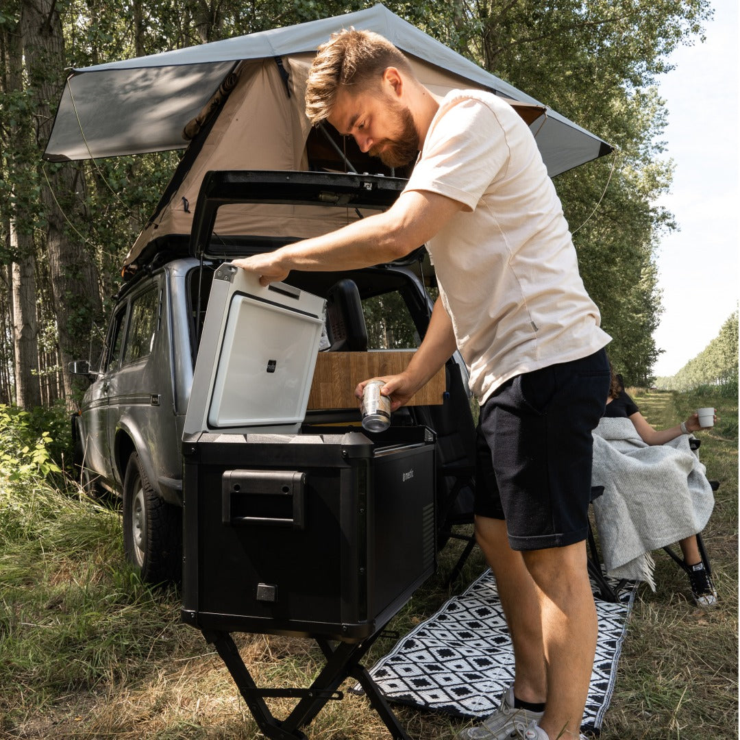 Mestic cool box on the MCCB-300 stand being opened beside a vehicle with roof tent