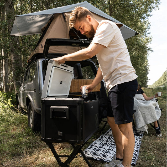 Cool box on a Mestic stand beside an adventure vehicle with a roof tent setup