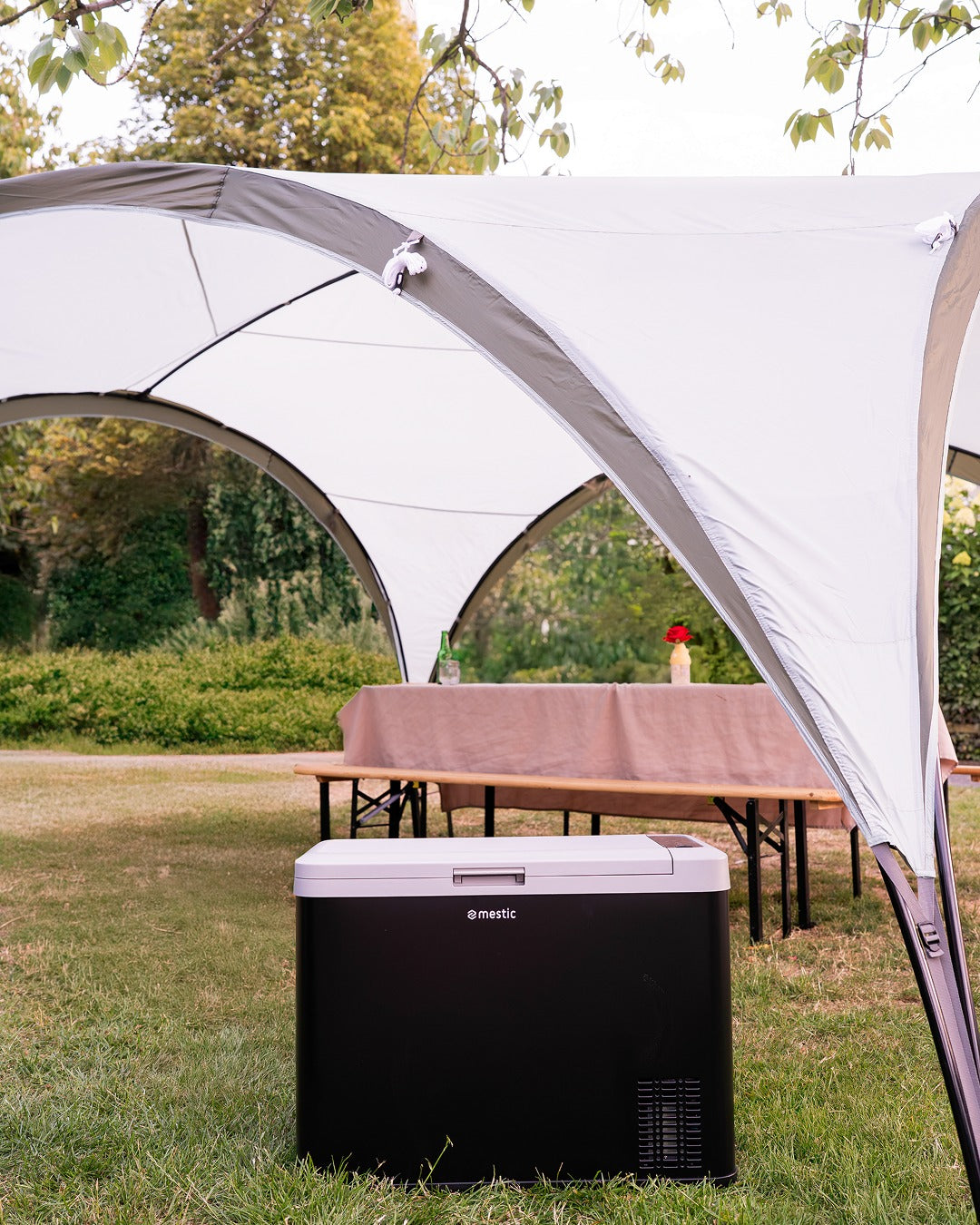 Mestic camping cool box sheltered under a canopy on a sunny day outdoors