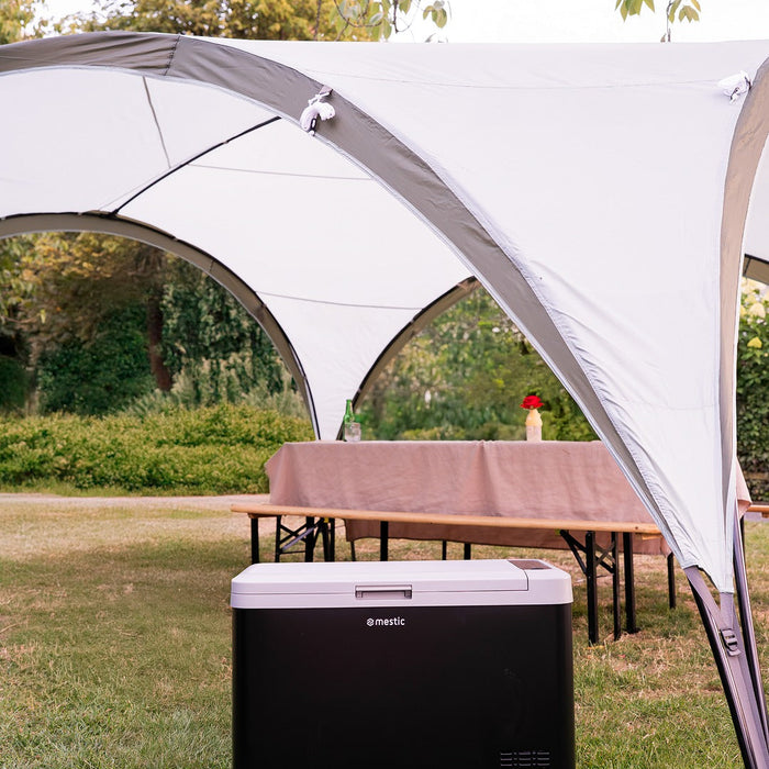 Mestic camping cool box sheltered under a canopy on a sunny day outdoors
