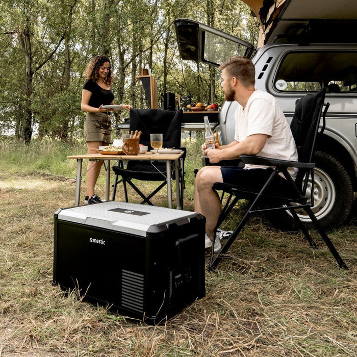 Outdoor camping scene with a Mestic compressor cool box beside the cooking area